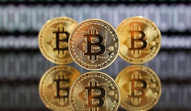 A collection of bitcoin tokens stand in front of an illustration of binary code in a photograph in London. Photo: Bloomberg