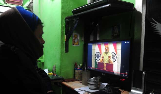 An Indian shopkeeper in Allahabad watches Prime Minister Narendra Modi’s New Year’s Eve address to the nation on demonetisation. Photo: AFP