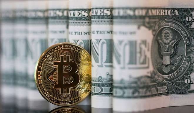 A bitcoin token stands next to a collection of US one dollar bills. Photo: Bloomberg