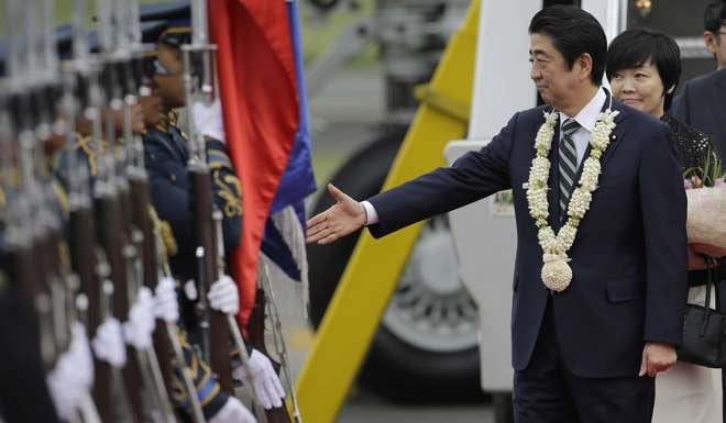 Japanese Prime Minister Shinzo Abe reaches out his hand beside his wife Aika as they arrive at Manila's airport. Photo: AP