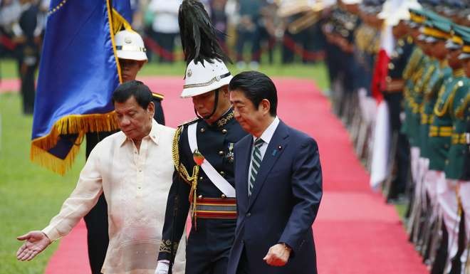 Philippine President Rodrigo Duterte gestures to Japanese Prime Minister Shinzo Abe as they review the troops during welcoming ceremony at the Malacanang Palace. Photo: AP
