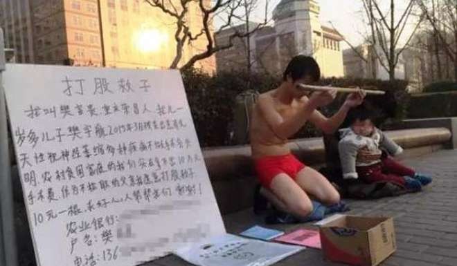 The man with his family on the street in Beijing. The message next to him explains that their son needs an operation to prevent him going blind. Photo: Thepaper.cn