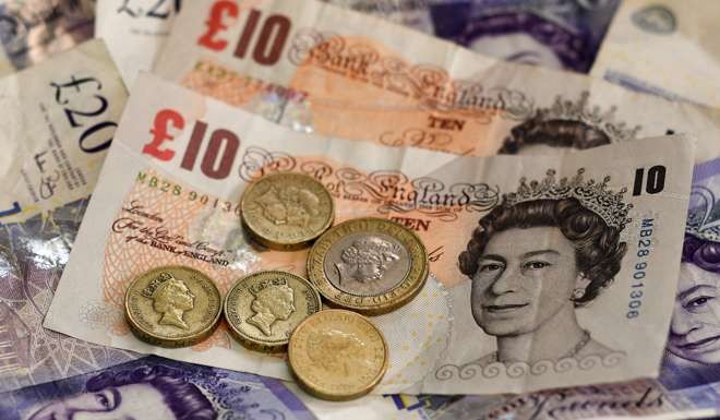 An arrangement of British 10 and 20 pound bank notes and 1 and 2 pound coins. London's FTSE 100 hit a fresh record high at the open on January 16, 2017 as the pound slumped to 32-month lows against the dollar over Brexit. Photo: AFP