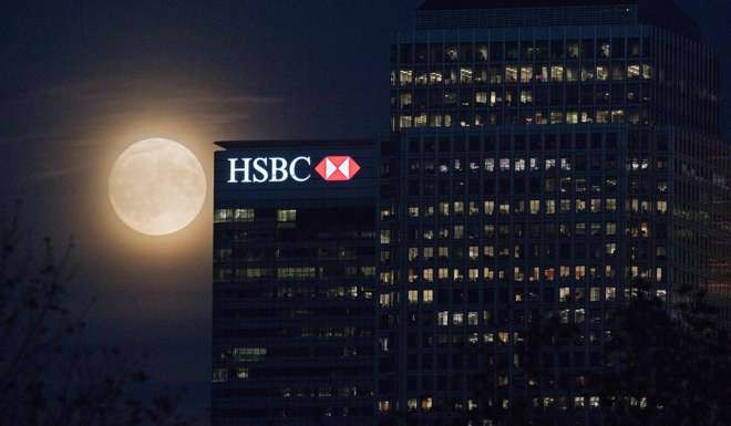 The moon rises behind HSBC bank in London's Docklands. Photo: AFP