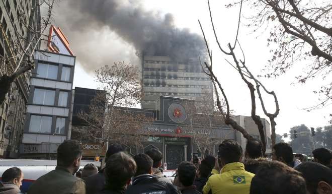 Iranians watch the Plasco building where smoke rises from its windows. Photo: AP