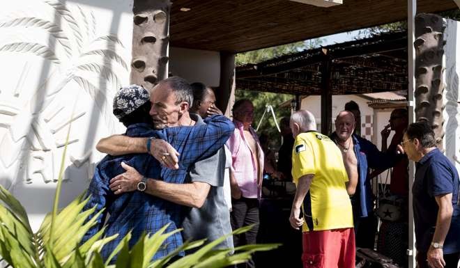 A Tourist embraces a local man as he and others prepare to leave their hotel in Banjul on Thursday. Photo: AFP
