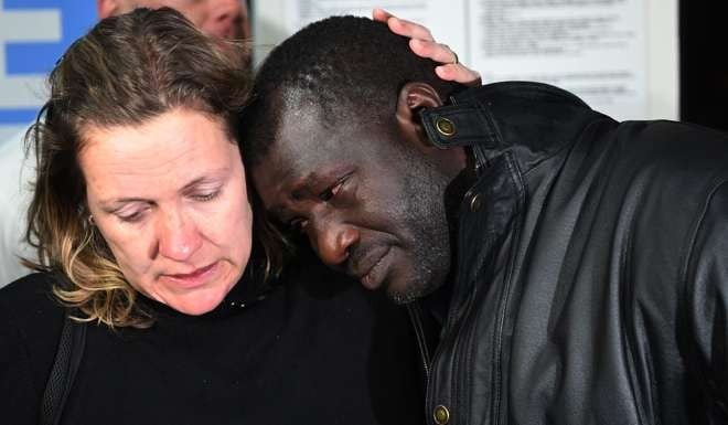 British traveller Sara Wilkins consoles fellow passenger Ebrima Jagne of Gambia after they arrived on repatriation flights organised by tour operator Thomas Cook at Manchester Airport in north west England on Thursday. Photo: AFP