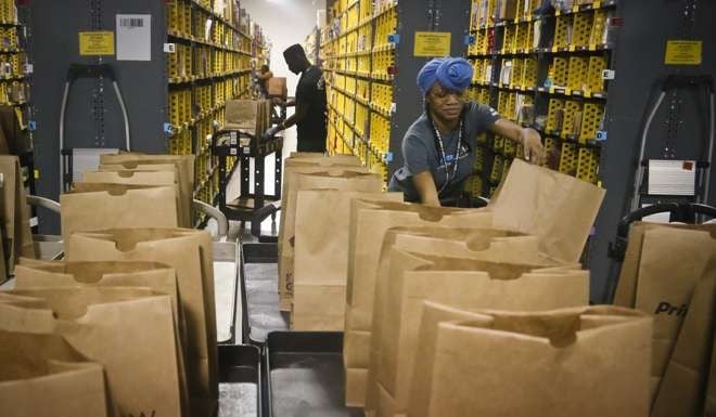 Miracle Stewart, right, an employee of Amazon PrimeNow, prepares bags to fill with orders from customers making purchases, at a distribution hub in New York. Amazon said it plans to hire 100,000 people across the U.S. over the next 18 months. Photo: AP