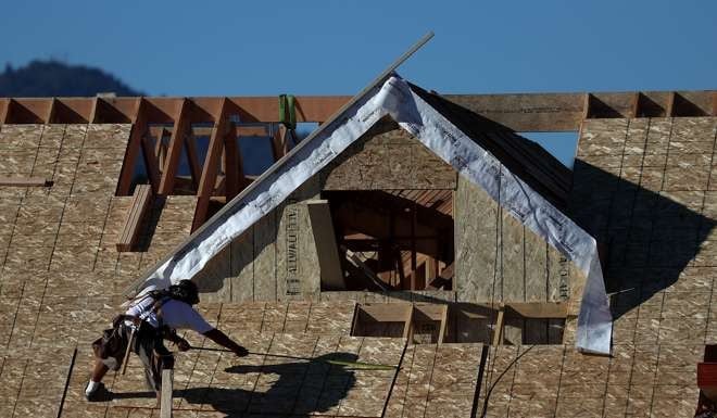 A worker standing on the roof of a home under construction at a new housing development in San Rafael, California. New construction of US homes surged in December compared to November, when the rate was revised up, closing a strong year for the housing market, the Commerce Department reported. Photo: AFP