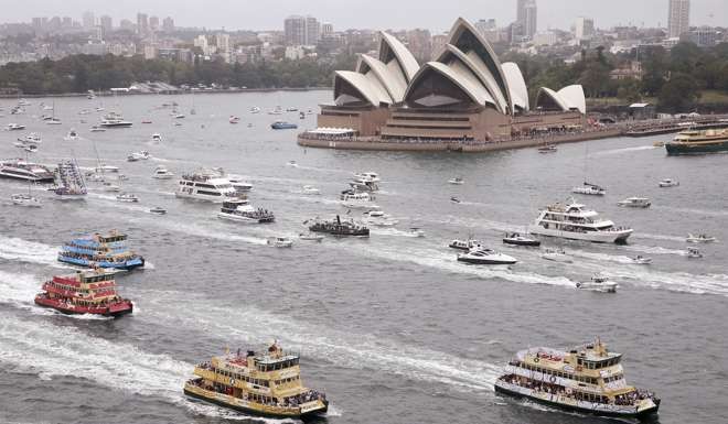 Competitors in the annual ferry boat race cruise past the Sydney Opera House as part of Australia Day celebrations in Sydney. Photo: AP