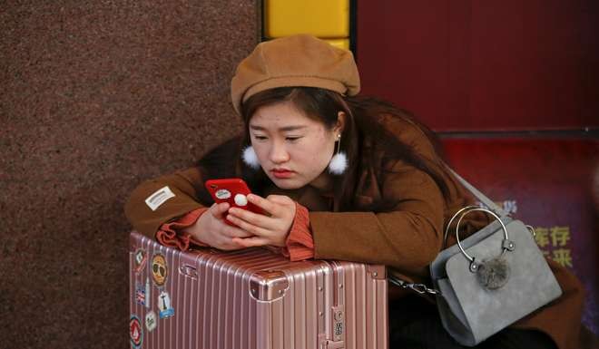 A passenger checks her phone at a waiting hall of Beijing Railway Station. Photo: Reuters