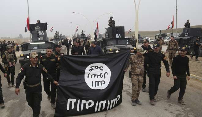 Iraq's special forces troops hold a flag of the Islamic State group during a parade to celebrate the fully liberation of the eastern side of Mosul. Photo: AP