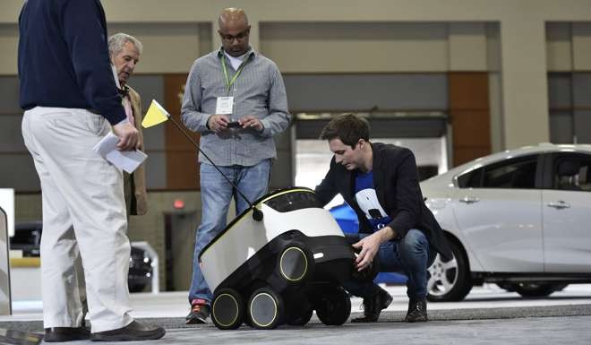 Henry Harris-Burland (right) with one of the delivery robot. Photo: AFP