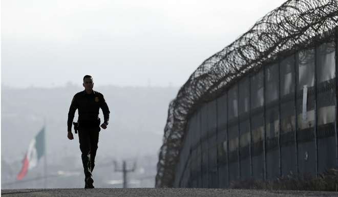 A US border patrol agent walks near the secondary fence separating Tijuana, Mexico, and San Diego, California. Photo: AP