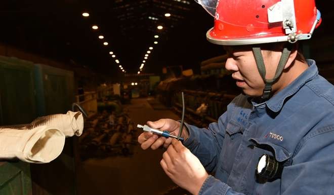 A worker checks newly produced steel components for pen tips at Taiyuan Steel. Photo: Xinhua