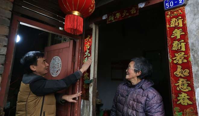 A volunteer pastes Lunar New Year couplets on the door of Liu Huiying’s home in Chongqing, on January 23. Volunteers visited Liu, who lives alone, and had a family reunion meal with her to celebrate Spring Festival. Photo: Xinhua