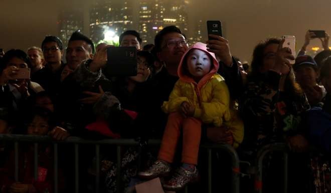 A crowd watches the Lunar New Year fireworks display over a cloudy Victoria Harbour on January 29. Hong Kong has experienced impressive economic growth in the past two decades, yet a great many people here are dissatisfied with their lives. Photo: Reuters