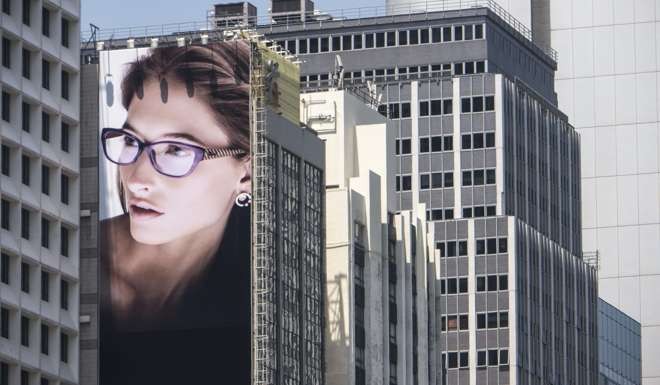 An advertising hoarding for a luxury brand of eye wear covers the side of a building in Central Hong Kong. Photo:EPA