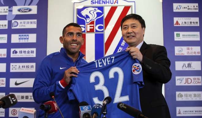 Carlos Tevez poses with his new Shanghai Shenhua jersey. Photo: AFP