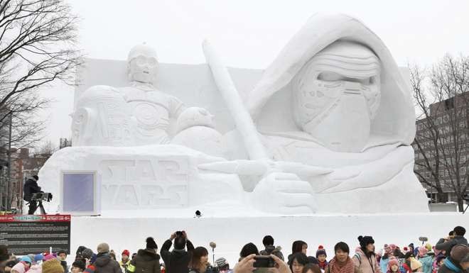 Tourists gather in front of a snow statue of characters from the