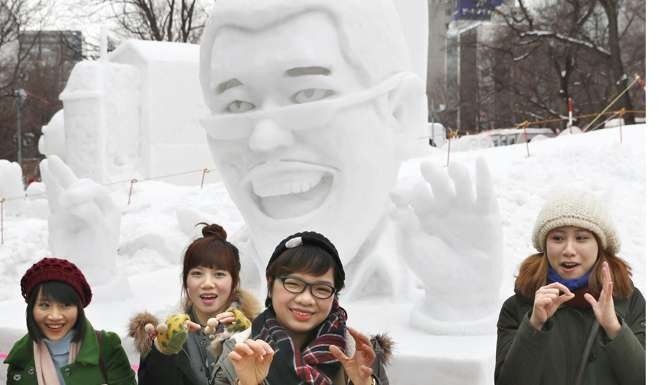 Tourists pose for photos in front of a snow statue of Japanese comedian Piko Taro, known for viral hit ‘Pen-Pineapple-Apple-Pen’. Photo: Kyodo