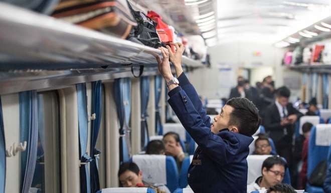Staff member Xie Zhiping stores baggage safely overhead on a train in Chongqing, in China’s southwest. Photo: Xinhua