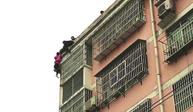 The woman dangling from ther edge of the building. Photo: Sohu.com